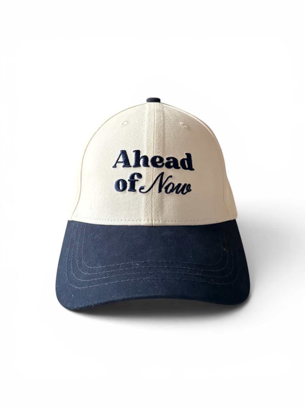 Cream and navy fashion cap, front view, with Ahead of Now embroidered logo